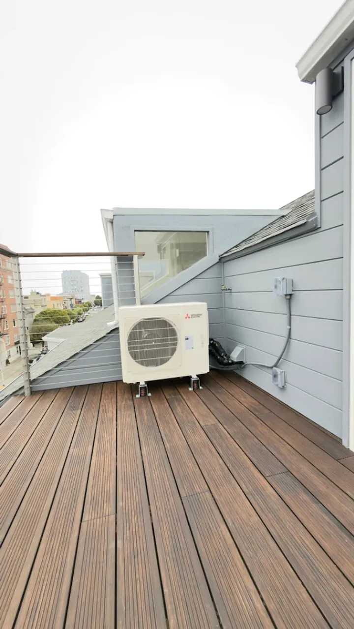 Compact outdoor HVAC unit beside a deck