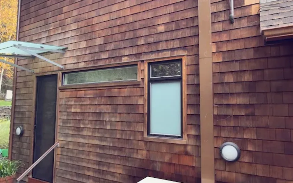 Outdoor mini-split unit beside a wood-sided home